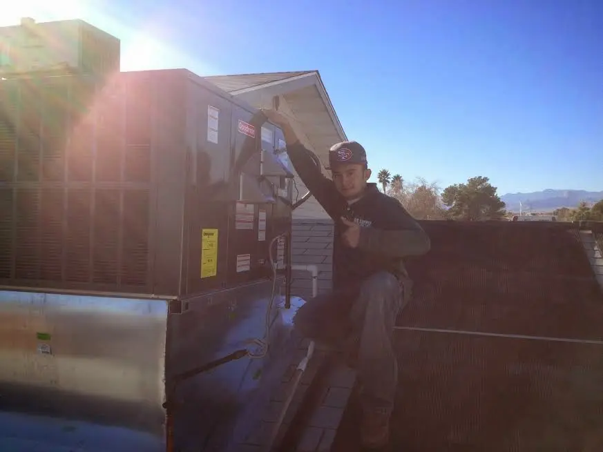 HVAC technician performing Boiler Repair on a rooftop unit in East Lansing
